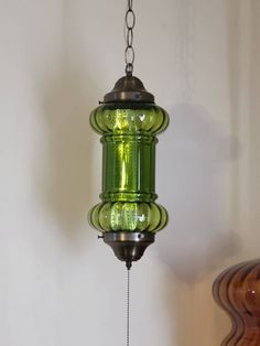 a green glass light hanging from a chain