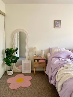 a bedroom with a bed, mirror and plant on the floor in front of it