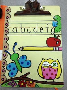 a clipboard with an owl, butterfly and apple on it next to a pencil