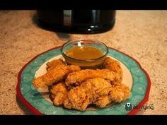 fried chicken on a plate with dipping sauce next to an air fryer in the background