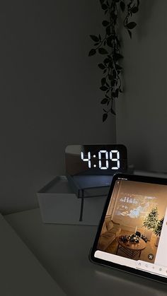 an alarm clock sitting on top of a table next to a laptop computer and tablet