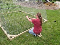 a woman kneeling down in front of a chicken coop