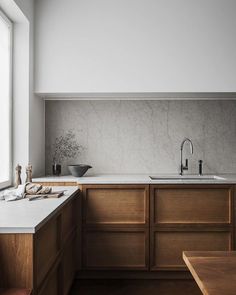 a kitchen with wooden cabinets and white counter tops, along with a sink that has no faucet