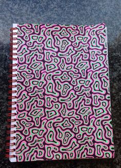 a spiral notebook with pink and green swirls on it