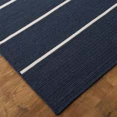 a blue rug with white stripes on it sitting on a wooden floor in front of a wood floor