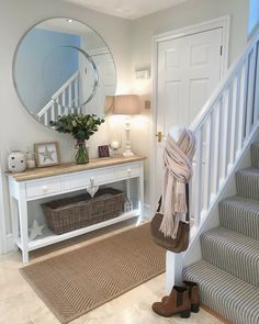 there is a white table with a mirror on it and a basket under the stairs