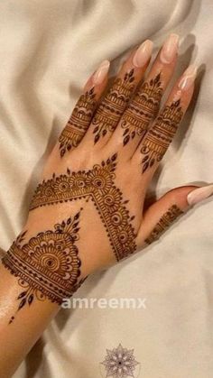 a woman's hand with henna tattoos on it