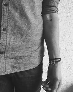 a man with a tattoo on his arm holding the hand of another person's wrist