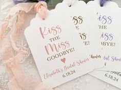 three tags that say kiss the miss goodbye and have pink ribbons around them on a lace tablecloth