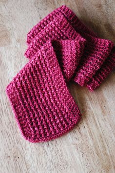 three crocheted pink mittens sitting on top of a wooden floor