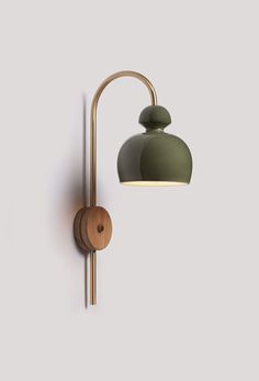 a wall light with a green shade on the side and a wooden object attached to it