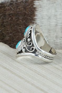 This Kingman turquoise and sterling silver ring was made by Navajo silversmith Calvin Belin. The inside is signed RB and stamped .925.Size: 14.25Length: 1 1/4"Width: 1 1/16"Free shipping on all orders! We ship with USPS and always include tracking. All orders ship within a day of payment.Returns are accepted up to 30 days after you receive your order. Just send us a message. Our shop offers cash back or store credit. The item must be returned in new condition. Southwestern Style Turquoise Open Ring In Sterling Silver, Western Silver Turquoise Ring Stamped 925, Southwestern Turquoise Ring In Sterling Silver, Southwestern Turquoise Open Ring In Sterling Silver, Western Style Turquoise Ring With Sterling Silver Inlay, Southwestern Sterling Silver Turquoise Open Ring, Western Style Sterling Silver Turquoise Inlay Ring, Western Style Turquoise Inlay Ring In Sterling Silver, Navajo Rings Turquoise