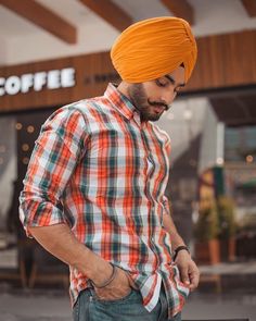 a man wearing an orange turban standing in front of a coffee shop