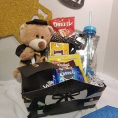 a teddy bear sitting on top of a black box filled with candy and other items