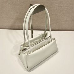 SHOP MORE LUXURY PRODUCTS HERE Description Prada Small Bag White For Women, Women’s Bags 9.8in/25cm 1BA368_2DDJ_F0009_V_OOO A study of the lines characterizes this smallÃƒÂ¯Ã‚Â¿Ã‚Â½ÃƒÂ¯Ã‚Â¿Ã‚Â½ÃƒÂ¯Ã‚Â¿Ã‚Â½ÃƒÂ¯Ã‚Â¿Ã‚Â½ handbag. It stands out for its absolutely elegant silhouette emphasized by the long, narrow handle. This three-pocket accessory is decorated with the metal lettering logo. Size: 25 x 13.5 x 13 cm /9.8 x 5.3 x 5 inches (Length x Width x Height) WhiteHandlesMetal hardwarePrinte Shopping Pouch Baguette Bag, Shopping Baguette Pouch Bag, Rectangular Baguette Bag With Top Handle For Errands, Shoulder Baguette Bag With Top Carry Handle For Errands, White Rectangular Hobo Bag With Top Carry Handle, Baguette Pouch Bag With Top Carry Handle For Shopping, Pouch-shaped Baguette Bag With Top Handle For Shopping, Classic Pouch Baguette Bag With Top Carry Handle, White Baguette Bag With Removable Pouch For Errands