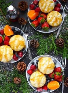 two white plates topped with muffins next to berries and pine cones