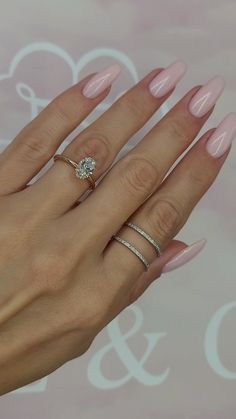 a woman's hand with pink manicured nails and two rings on her fingers