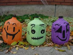 three painted pumpkins sitting on the ground next to each other with faces drawn on them