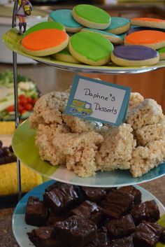 three tiered plates filled with cookies and pastries next to other desserts on display