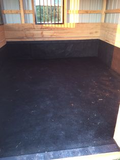 the inside of a horse trailer with black flooring and walls, windows, and bars