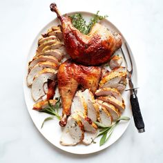 a white plate topped with sliced turkey and garnished with herbs next to a fork