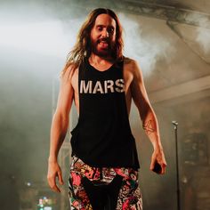 a man with long hair standing on stage