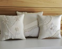 two white pillows sitting on top of a bed next to each other with flowers and leaves