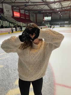 a woman standing on top of an ice rink holding her hands to her face and covering her eyes