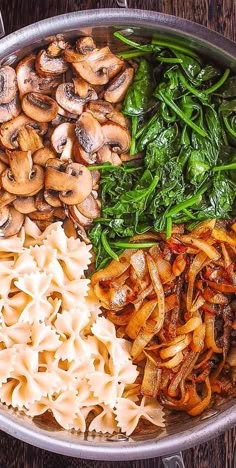 an assortment of pasta, mushrooms and spinach in a bowl