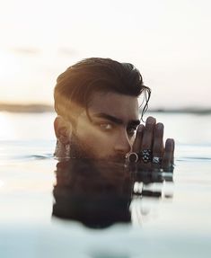 a man is floating in the water with his hands on his face and looking into the distance