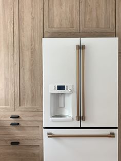 a white refrigerator freezer sitting inside of a kitchen next to wooden cupboards and drawers