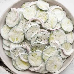 a bowl filled with sliced up cucumbers on top of a marble countertop