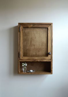 a wooden shelf with some flowers in it and a vase on the wall next to it