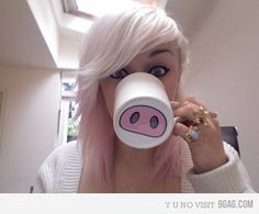 a woman with pink hair is drinking from a cup that has a pig face on it