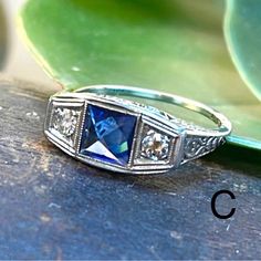 a blue stone ring sitting on top of a wooden table next to a green leaf