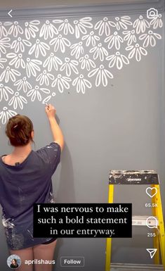 a woman is painting a wall with white stencils on it and the words, i was nervous to make such a bold statement in our entryway