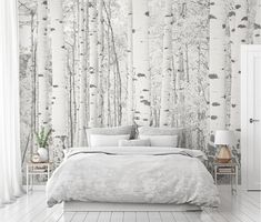 a bed sitting under a wallpaper covered in lots of white birch trees on top of a wooden floor