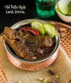 old delhi style lamb keema served in a copper bowl with sliced limes on the side