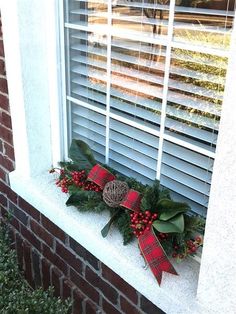 a window sill decorated with holly and plaid ribbon, red berries and greenery