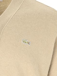 Lacoste X Comme des Gar s asymmetrical cardigan in beige wool with V-neck, chest logo patch, button closure, ribbed trim, and asymmetrical hem. composition: 100% woolsize and fit: adjust New Shirt Design, Asymmetrical Cardigan, Comme Des Garcons Shirt, Luxury Shop, Asymmetrical Hem, Comme Des Garcons, Luxury Retail, Japanese Fashion, Asymmetric Hem