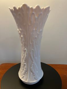 a white vase sitting on top of a wooden table