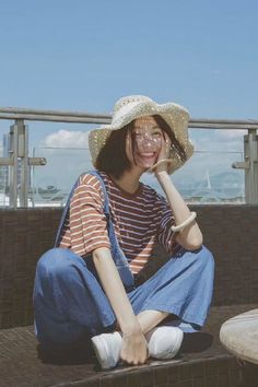 a woman sitting on the ground wearing a straw hat