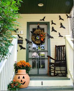 a front porch decorated for halloween with pumpkins and bats