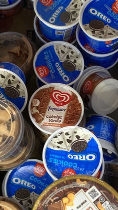 an assortment of ice creams and cookies in plastic containers with lids on display for sale