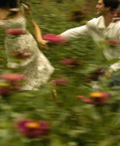 a man and woman are running through flowers