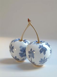 two blue and white porcelain cherries with gold handles, one on top of the other