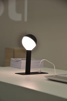 a desk lamp sitting on top of a table next to a laptop