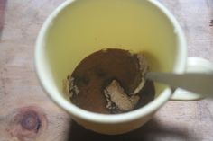 a cup filled with dirt sitting on top of a wooden table