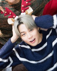 two young men sitting next to each other with reindeer antlers on their heads,