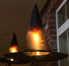 some lights that are on the side of a brick building and one is wearing a witches hat